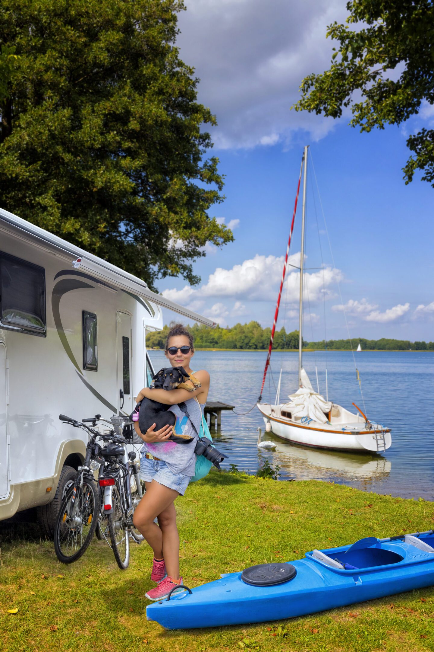 Woman with dog near camper and lake.